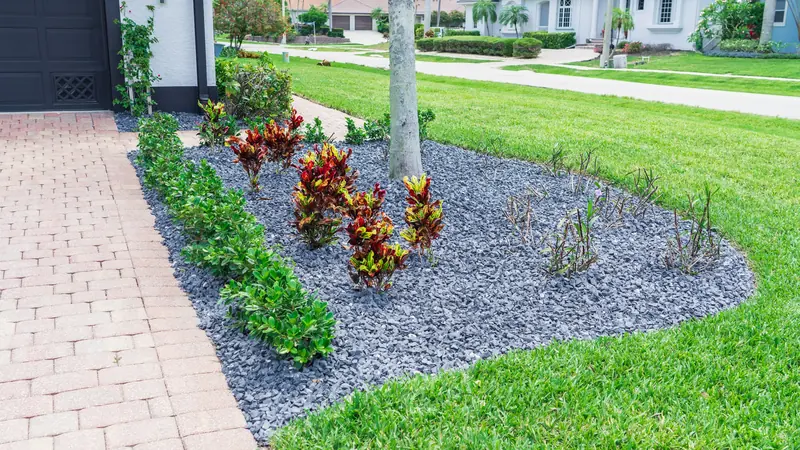 Planting bed dressed with dark decorative rock, crotons and low shrubs